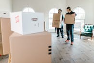 Man in Blue Denim Jeans Holding Brown Cardboard Box