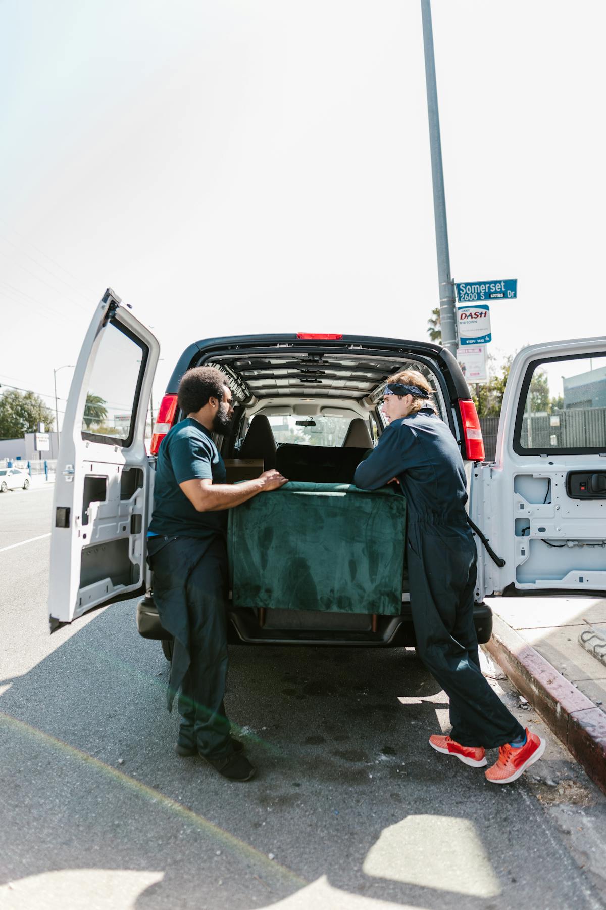 Two movers loading furniture into a van on moving day with cargo secured