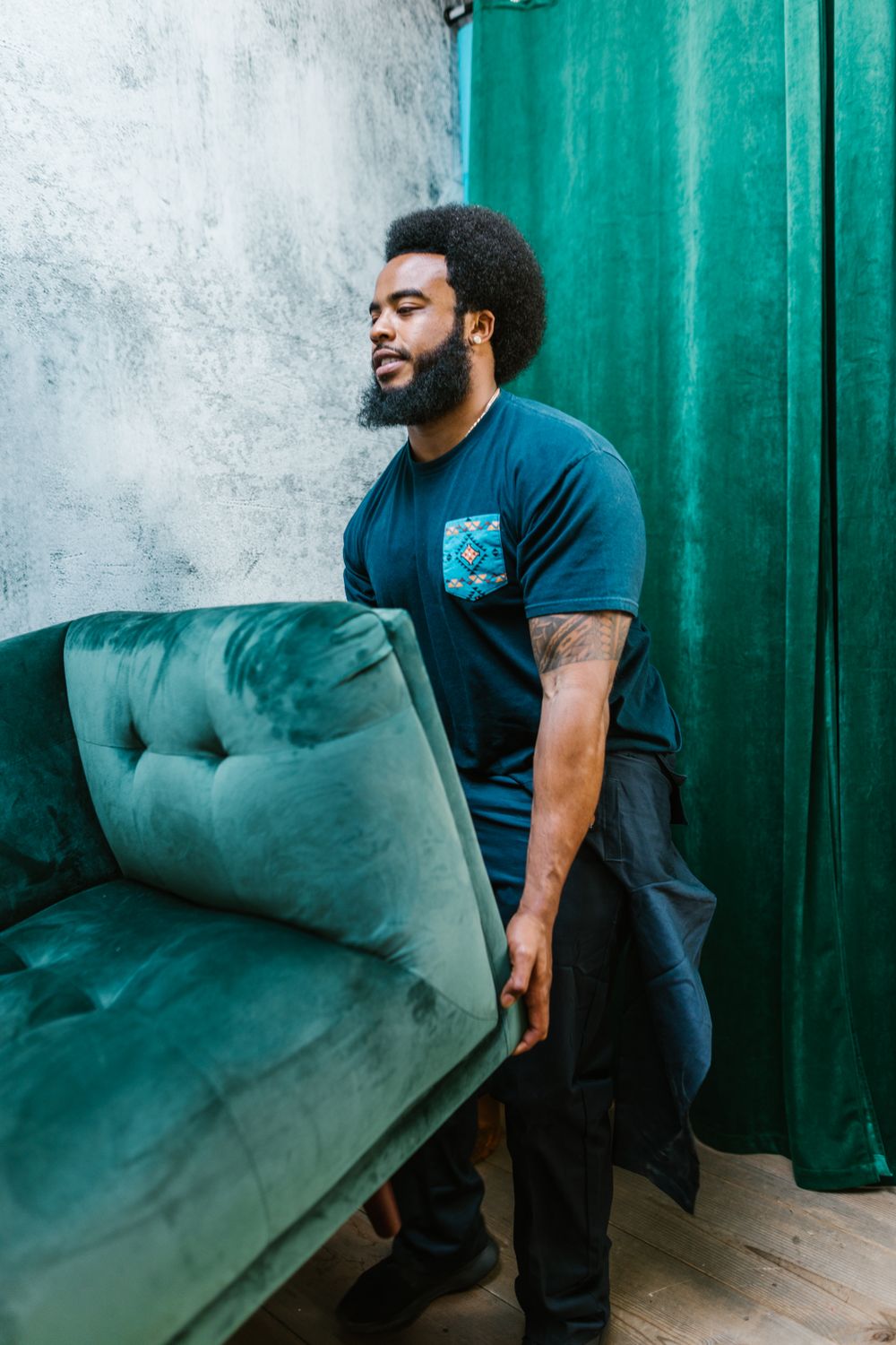 Bearded mover carrying a green couch for single furniture moving in Dubai
