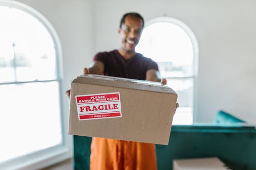 Free Man in Black Jacket Holding Brown Cardboard Box Stock Photo