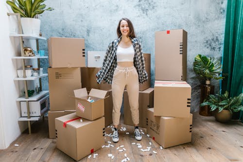 Free Photo of a Woman in a White Crop Top Standing Beside Cardboard Boxes Stock Photo