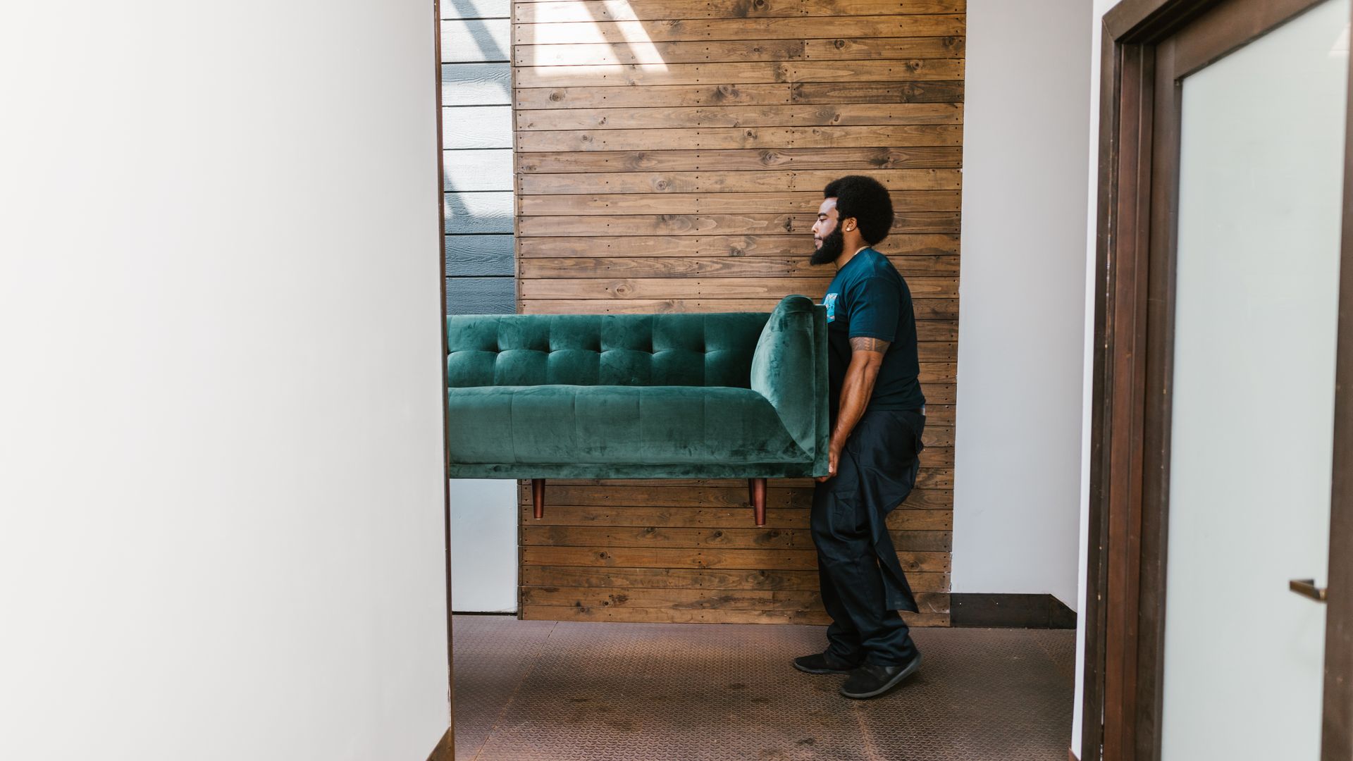 Professional movers carefully carrying a sofa from a property