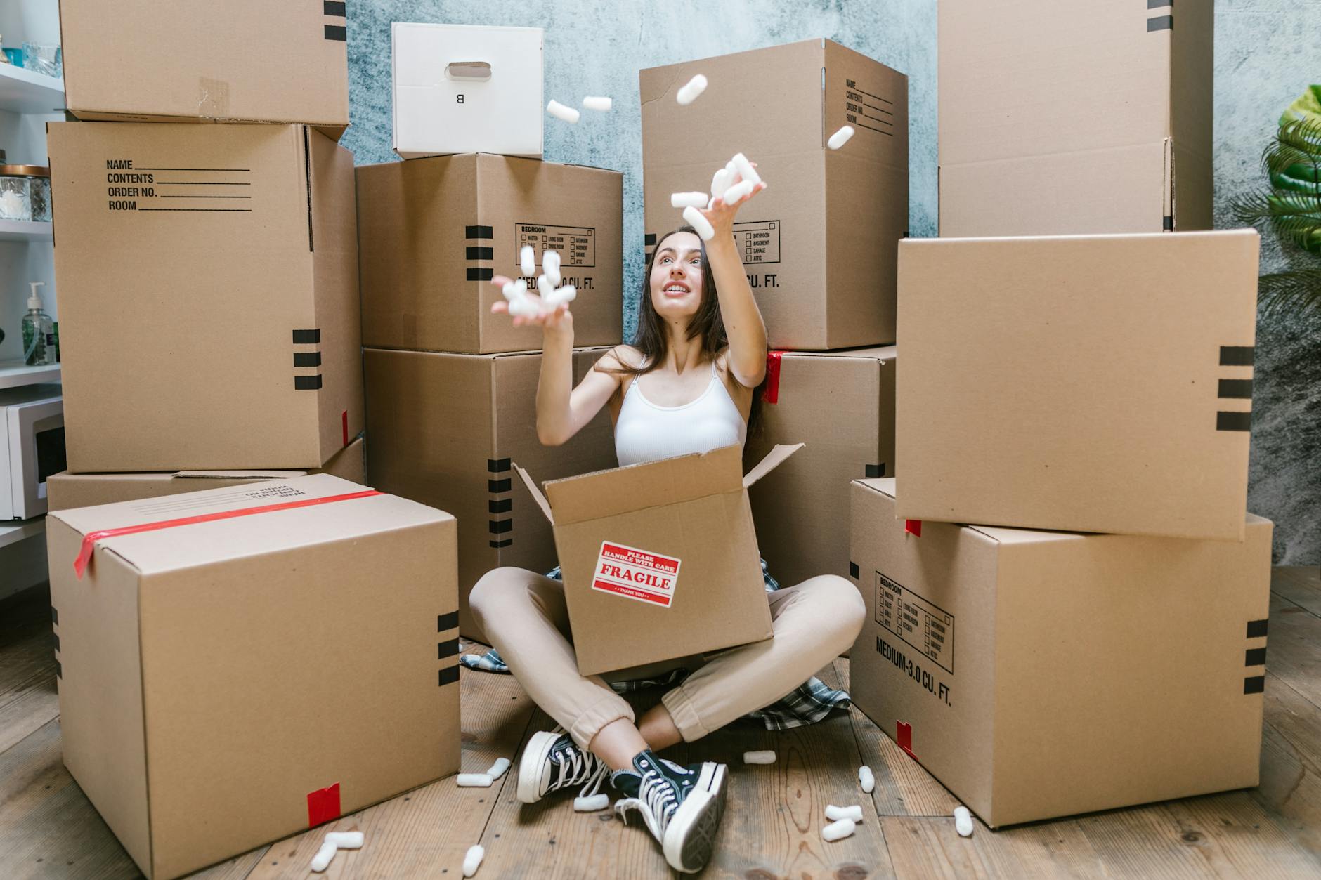 Woman in Black Tank Top Sitting on Brown Cardboard Box