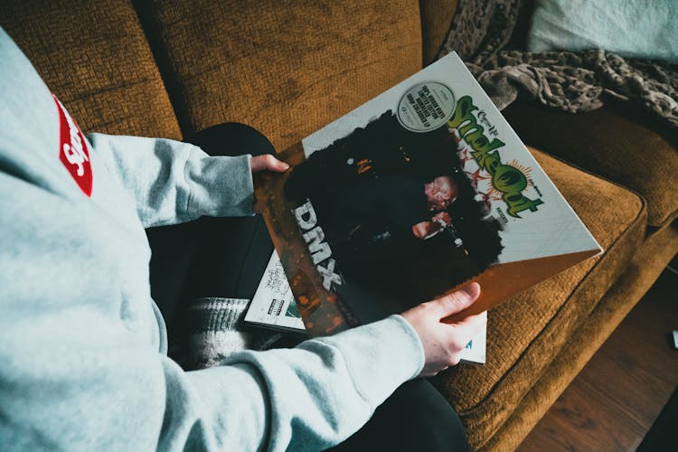 Person Sitting On Sofa And Showing Vinyl Record In Cover