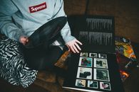 From above of crop unrecognizable person in casual clothes sitting on sofa and taking vinyl record at home in daytime