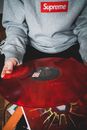 From above of crop anonymous person holding transparent red vinyl record at home