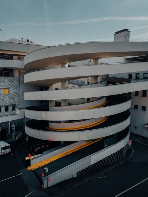 Exterior of modern multistory car park with spiral ramp located on city street in evening