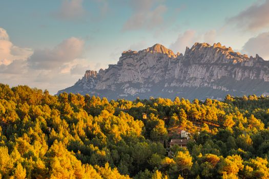 Stunning aerial view of Montserrat mountains, surrounded by lush forests at sunset in Spain.