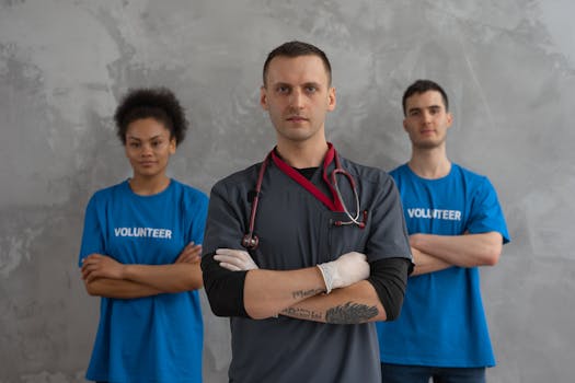 Healthcare worker with stethoscope and volunteers standing in solidarity indoors.