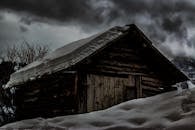 冬日天空阴沉，积雪覆盖着神秘的乡村小屋