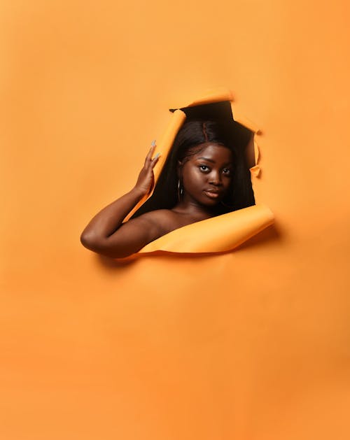 Studio Shoot of a Woman Coming out from an Orange Background