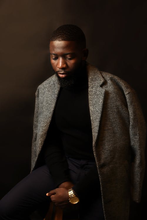 Man Wearing a Gray Coat Sitting on a Stool