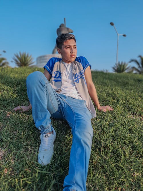 Teenage Boy in Denim Jeans Sitting on Grass