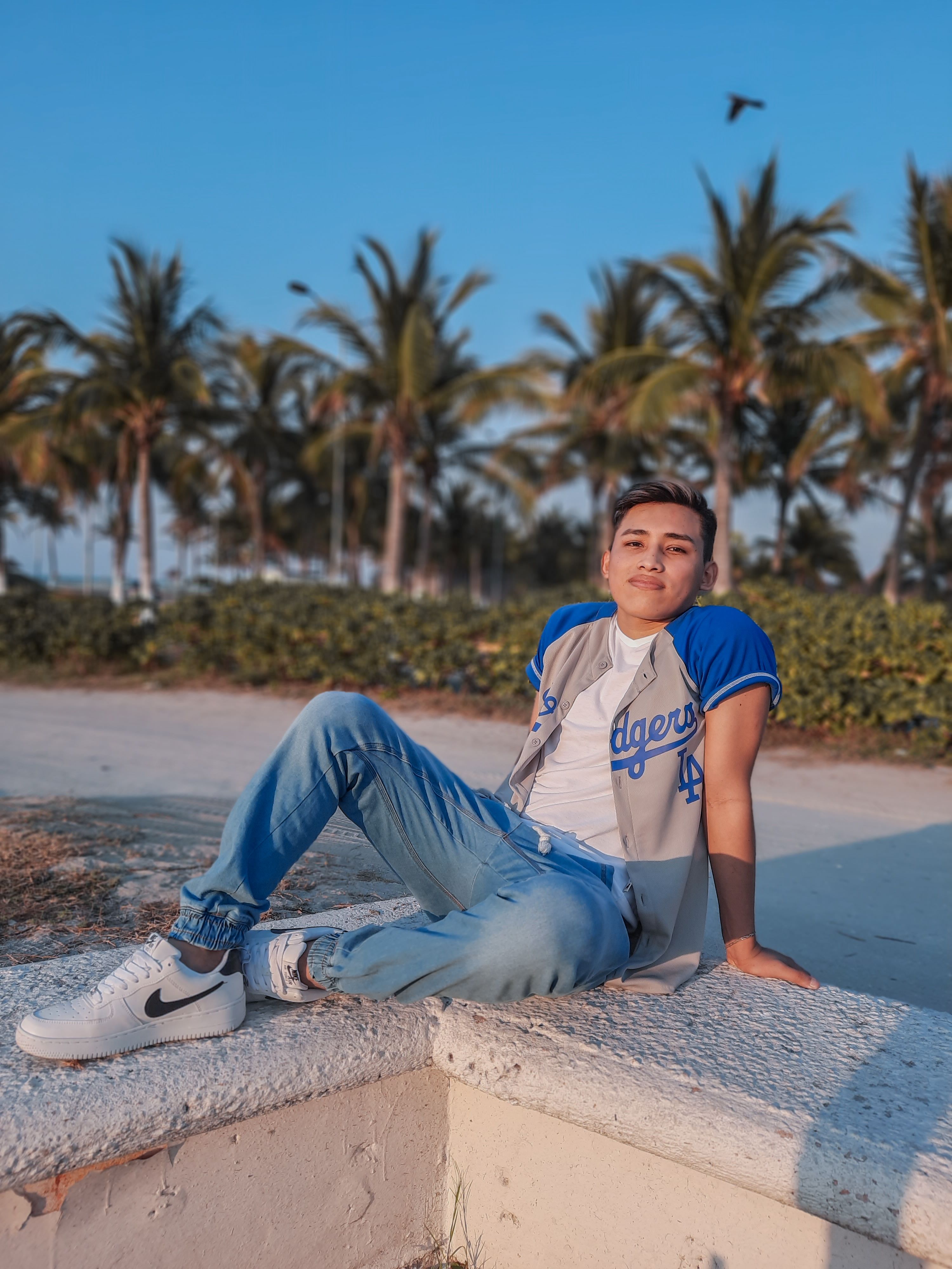 Casual portrait of a man sitting on a beach with palm trees in the background.
