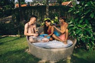 三个朋友在户外享受阳光明媚的一天，同时在花园座位上放松