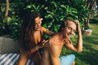 一对夫妇在郁郁葱葱的热带环境中涂抹防晒霜，享受夏日休闲和护肤