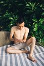 Topless Man in Gray Shorts Sitting on Brown Wicker Armchair
