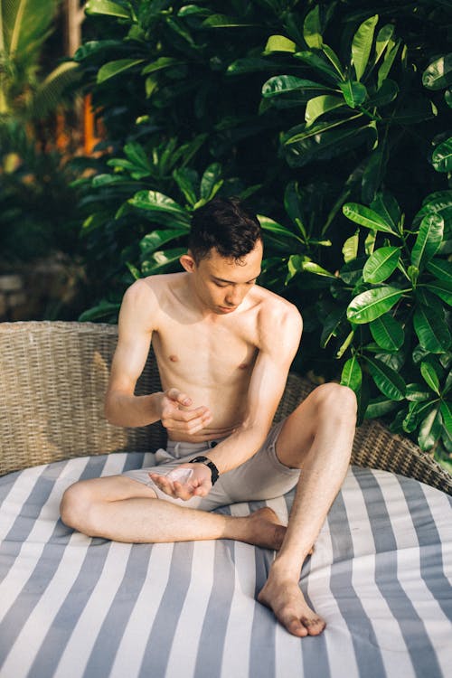 Free Shirtless Man Sitting and Putting Sunscreen Stock Photo