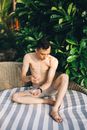 Topless Man Sitting on Brown and White Plaid Sofa Chair