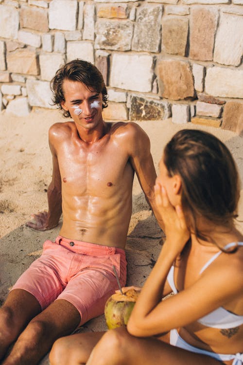 Free Topless Man and Woman Sitting on Sand Stock Photo