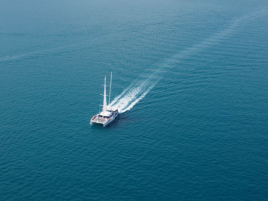 Best Private Luxury Sportfishing Experience Aboard Limitless Review: The Ultimate Oahu Yacht Charter Adventure Review 2026 - A sailboat cruises through clear blue ocean waters, captured from an aerial perspective.