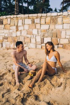 A couple sitting on the sandy beach, enjoying a relaxing day in the sun.