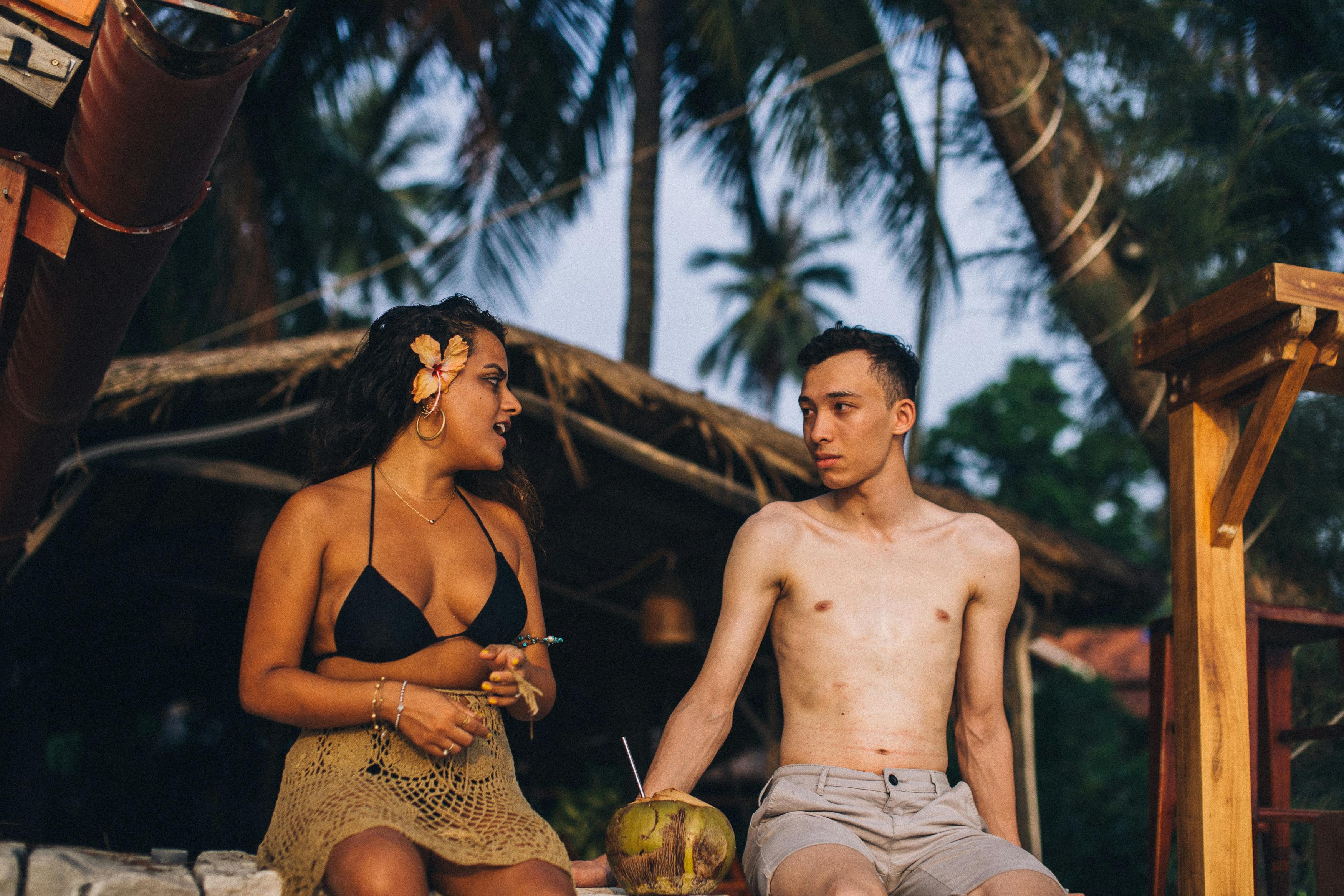 topless man in brown and black leopard print bikini bottom sitting on brown wooden bench during