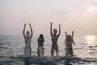 在美丽的日落时分，四个人欢快地在海里泼水的剪影