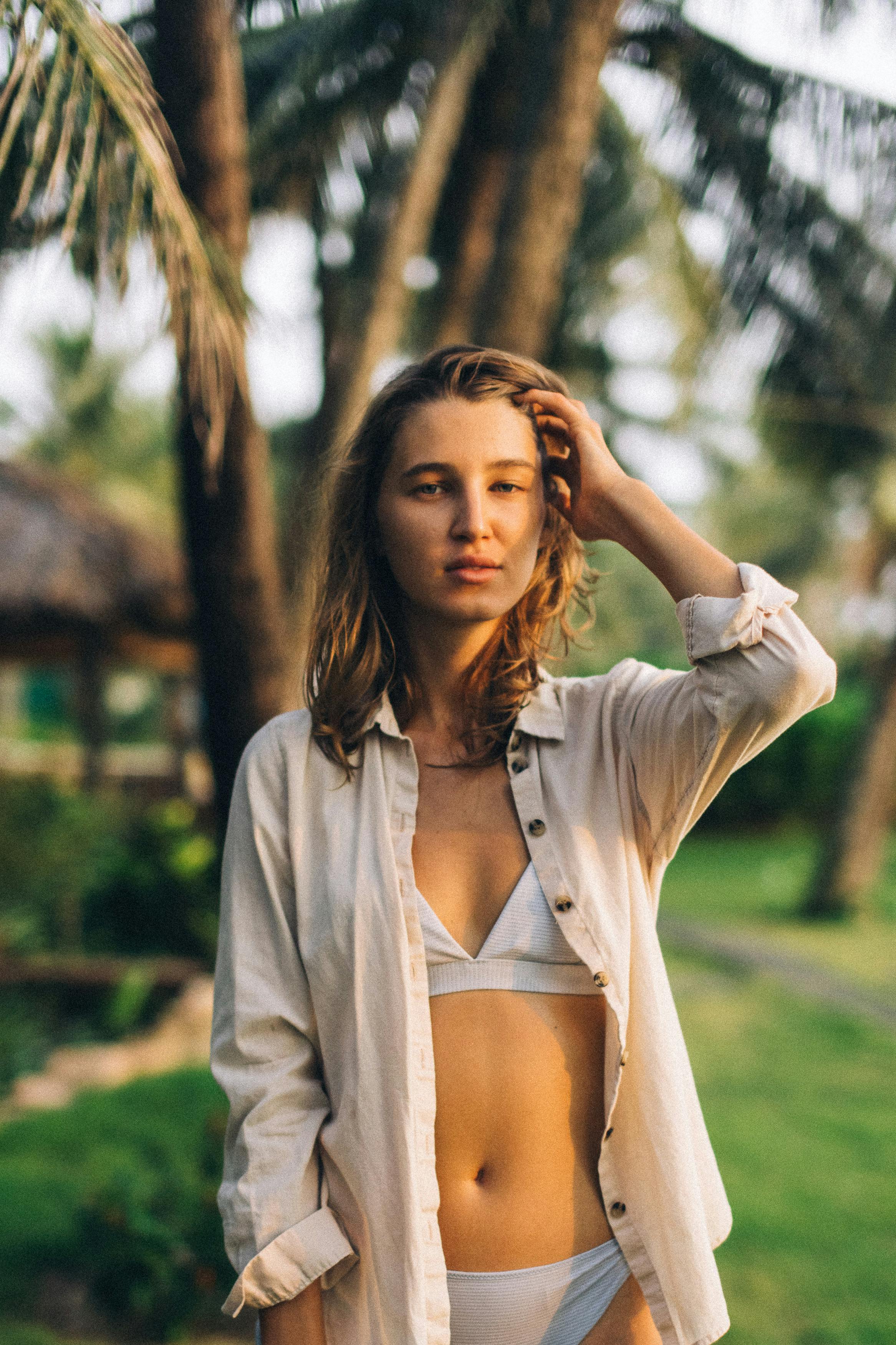 gratis Vrouw In Witte Bikini Raakt Haar Haar Aan Terwijl Ze Naar De Camera Kijkt Stockfoto