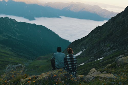 Two Person Sitting on Edge of Mountain Photograph