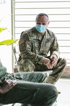 Photo by RDNE Stock project US Army soldier in uniform and mask, engaging in conversation indoors.