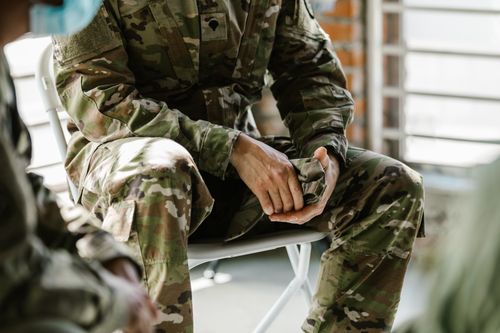 Free A soldier in camouflage uniform sitting indoors, representing military life and service. Stock Photo
