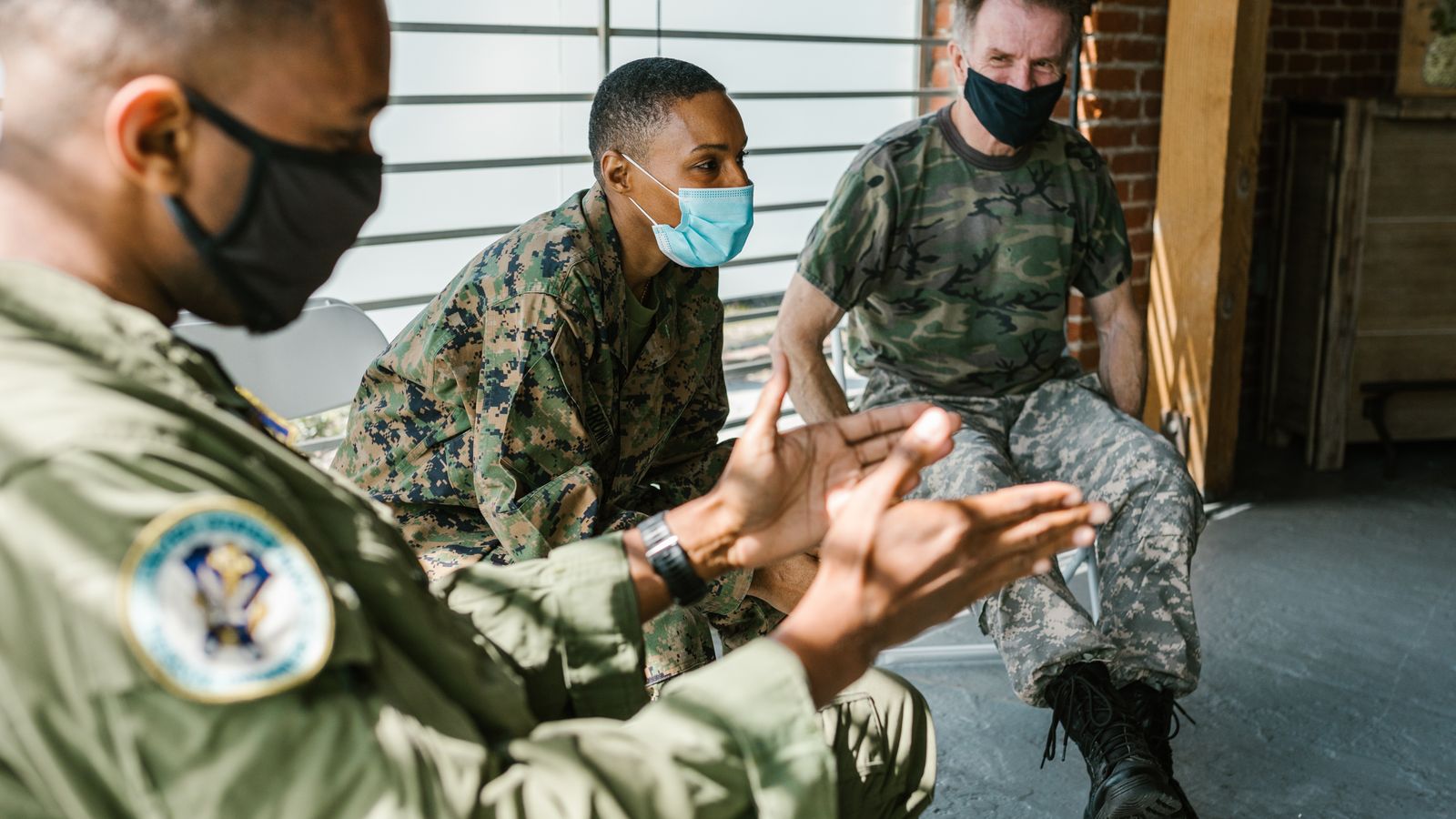 Veterans in military uniform participating in a group therapy session indoors.