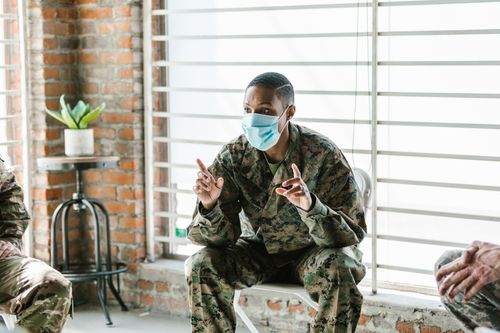 Free A military soldier wearing a facemask converses indoors, symbolizing communication and safety. Stock Photo