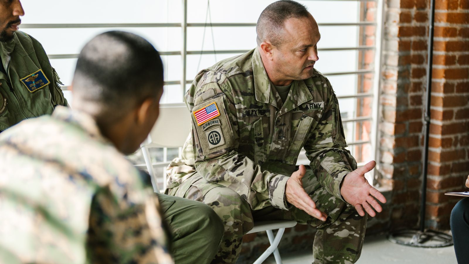 Military veterans engaging in a supportive group therapy session indoors.