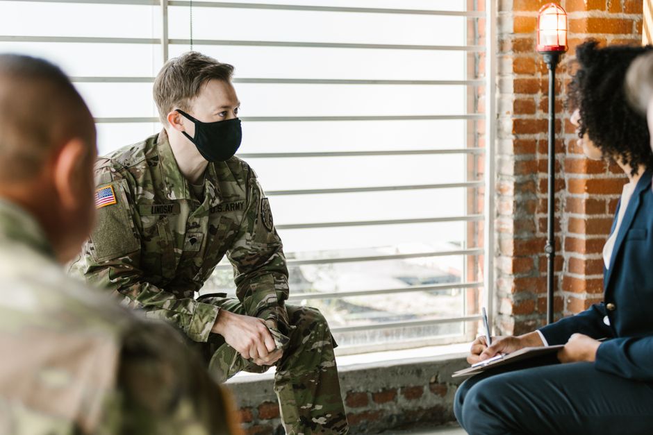 US Army personnel in a group therapy session with mental health professionals indoors.