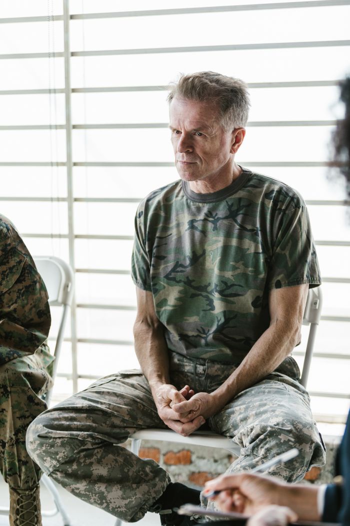 Senior veteran in camouflage uniform listening attentively in a counseling session