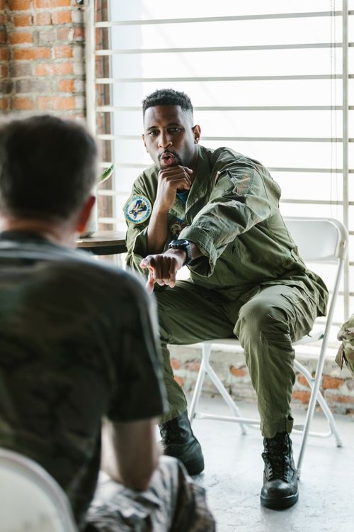Free African American military officer in debriefing session with soldiers indoors. Stock Photo
