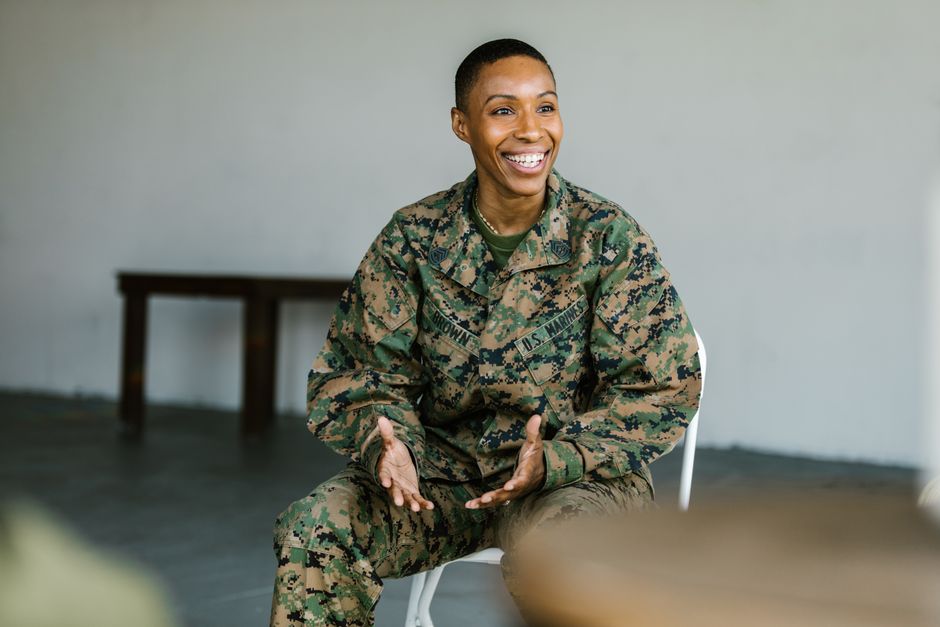 A happy female soldier in uniform smiling and talking indoors.