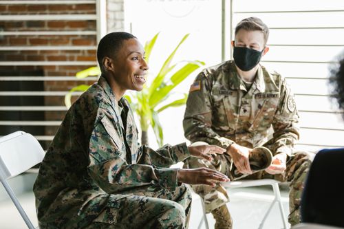 Free Soldiers in military uniforms discussing during a therapy session indoors. Stock Photo