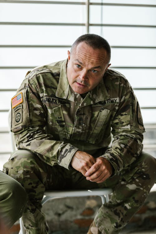 Photo of Man in Green Camouflage Uniform Sitting on Chair