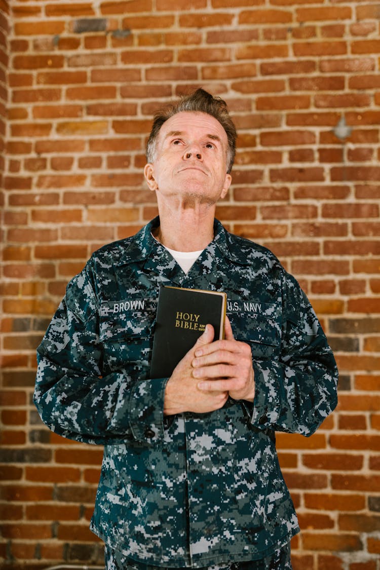 Photo Of US Navy Soldier Looking Up While Holding Bible