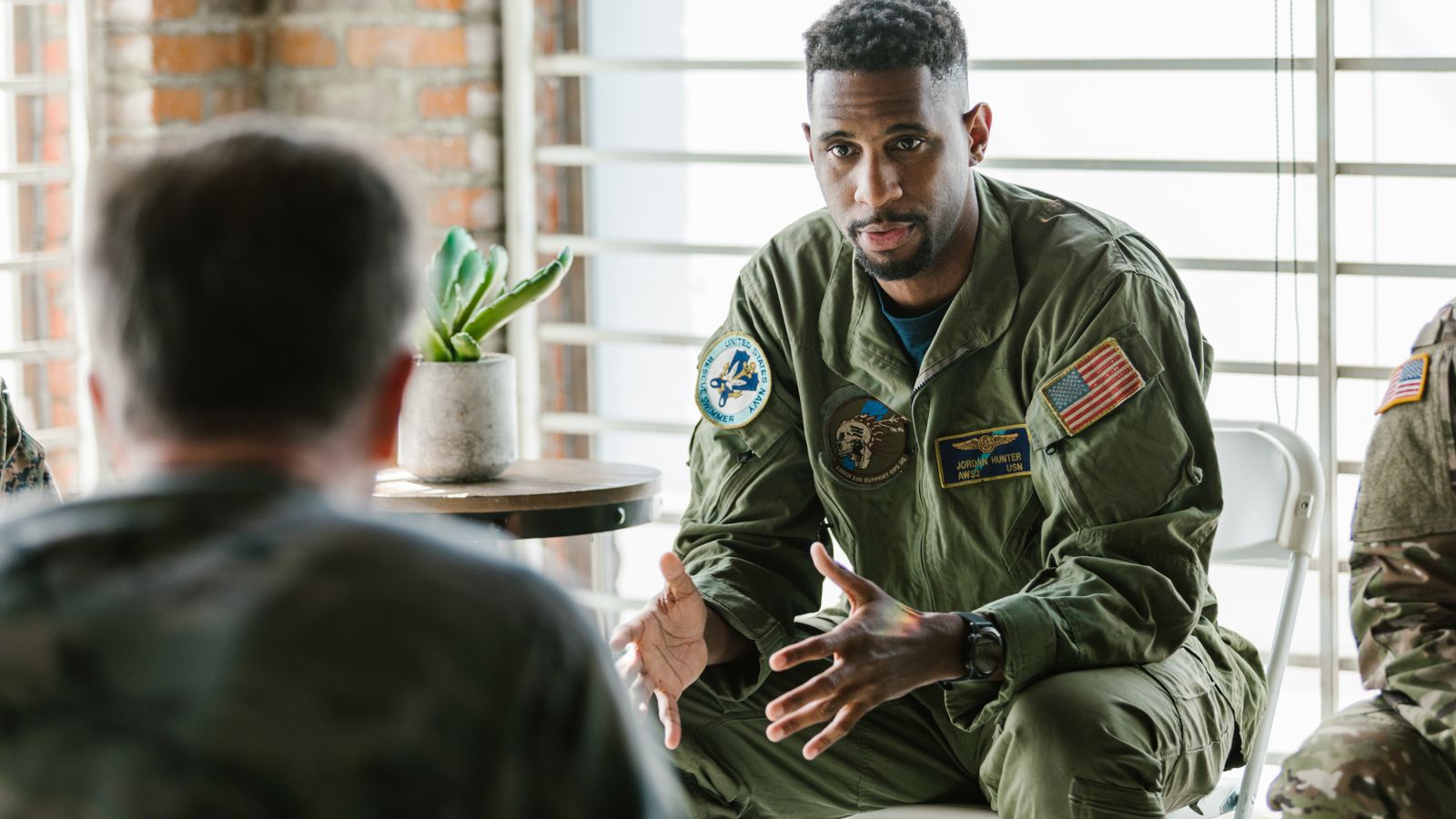 A group of military veterans participate in a supportive therapy session indoors.
