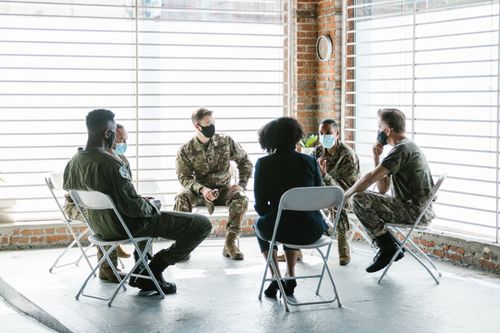 Free A group therapy session with soldiers in military uniform and face masks indoors. Stock Photo