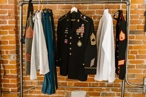 Free Military uniforms with badges hanging against a brick wall background. Stock Photo