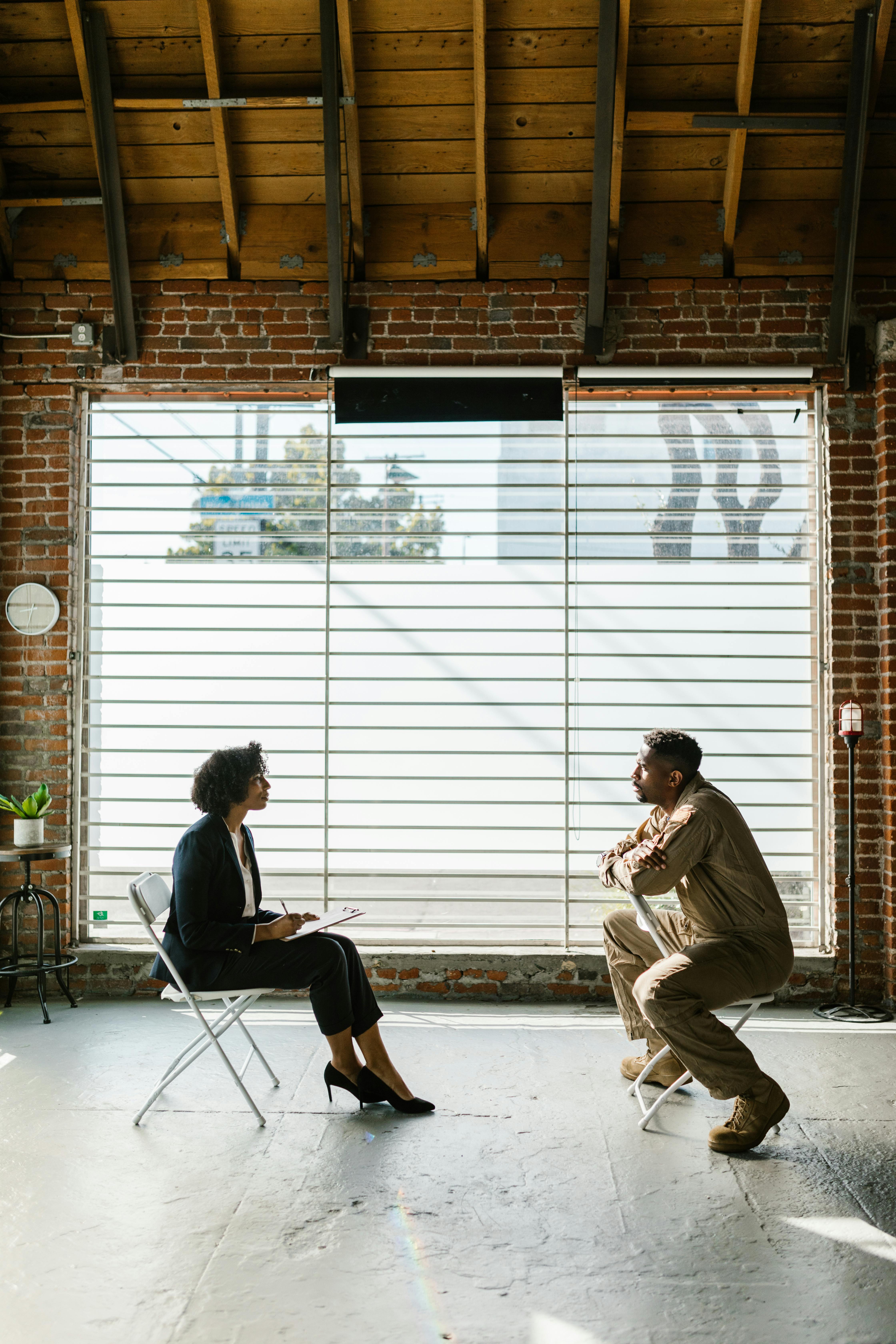 photo of man and woman sitting beside window