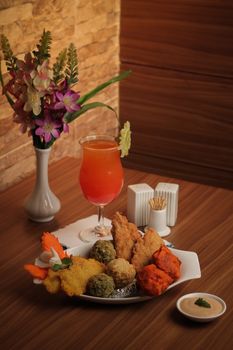 Colorful display of assorted fried foods with a tropical cocktail on a wooden table.