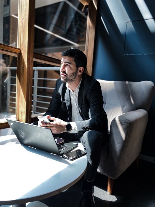 Free Man in suit working on laptop and smartphone in modern office lounge. Stock Photo