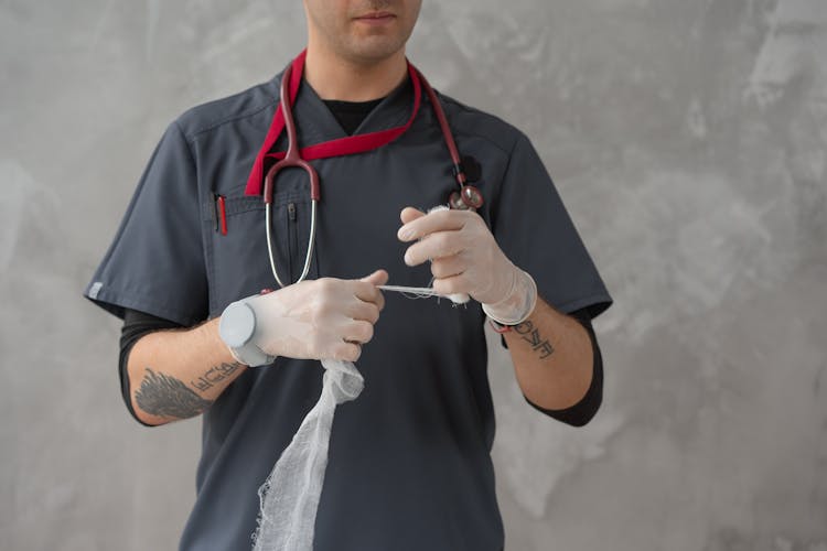 Person Wearing Surgical Gloves Holding A Gauze