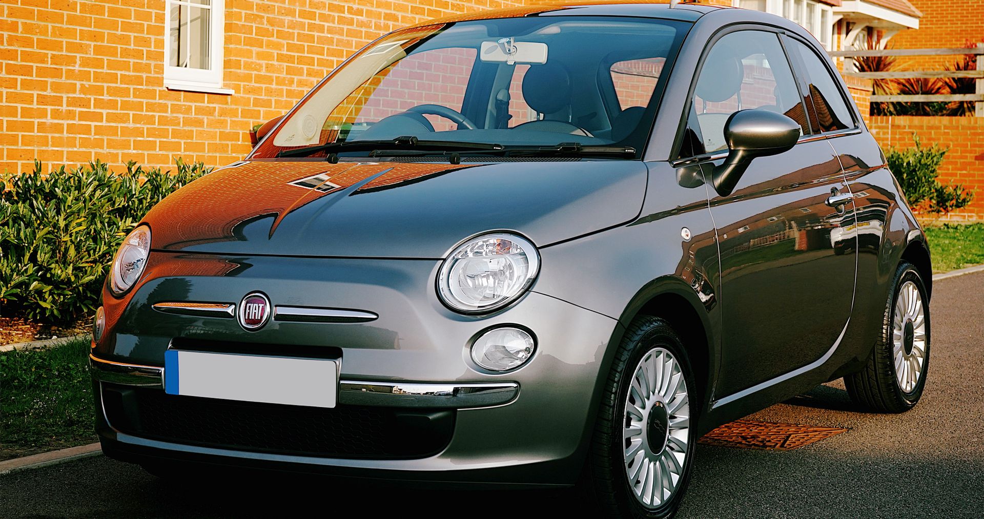 Close-up of a Fiat hatchback car parked in a suburban UK neighborhood during the day.